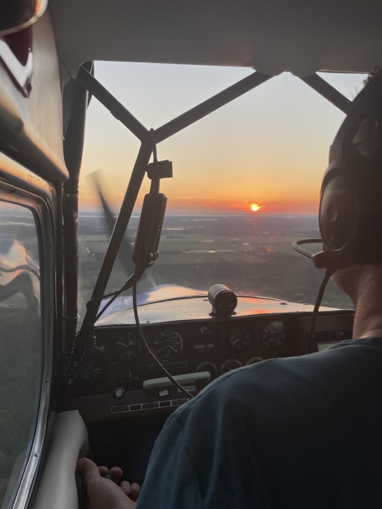 Pilot in the cockpit of a small aircraft during sunset